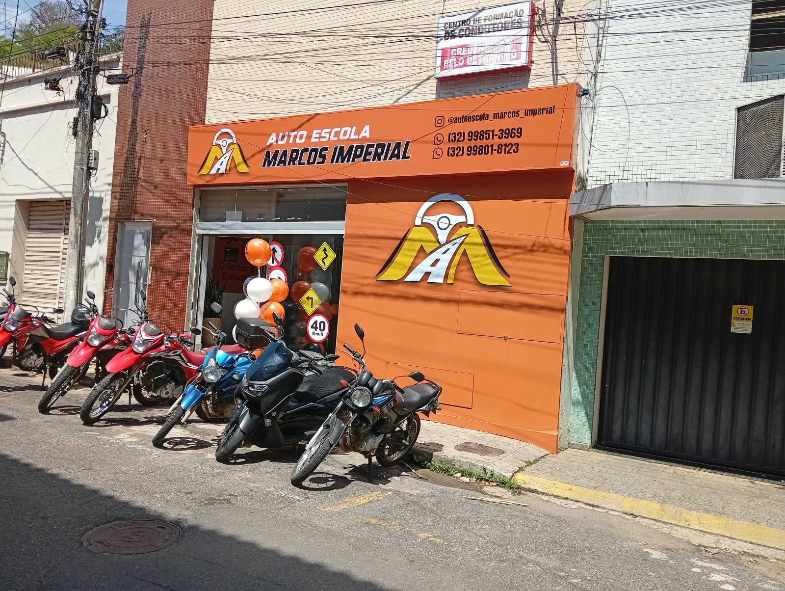 Fachada da Auto Escola Marcos Imperial em Muriaé, MG, com motocicletas estacionadas em frente à autoescola